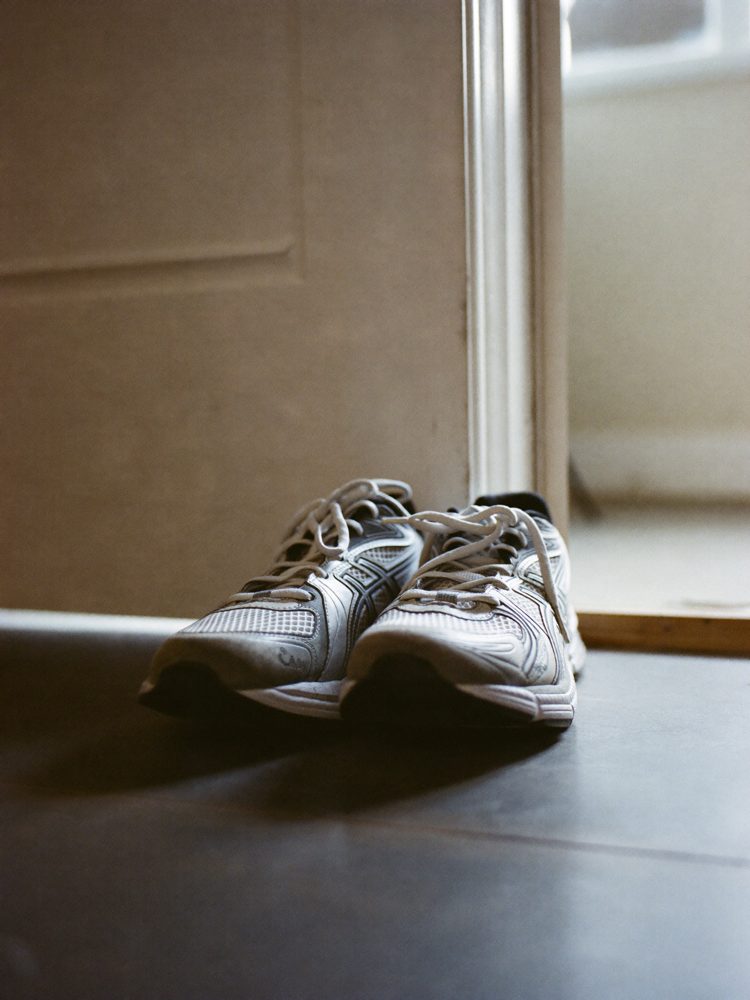 Unused running shoes gathering dust by a door